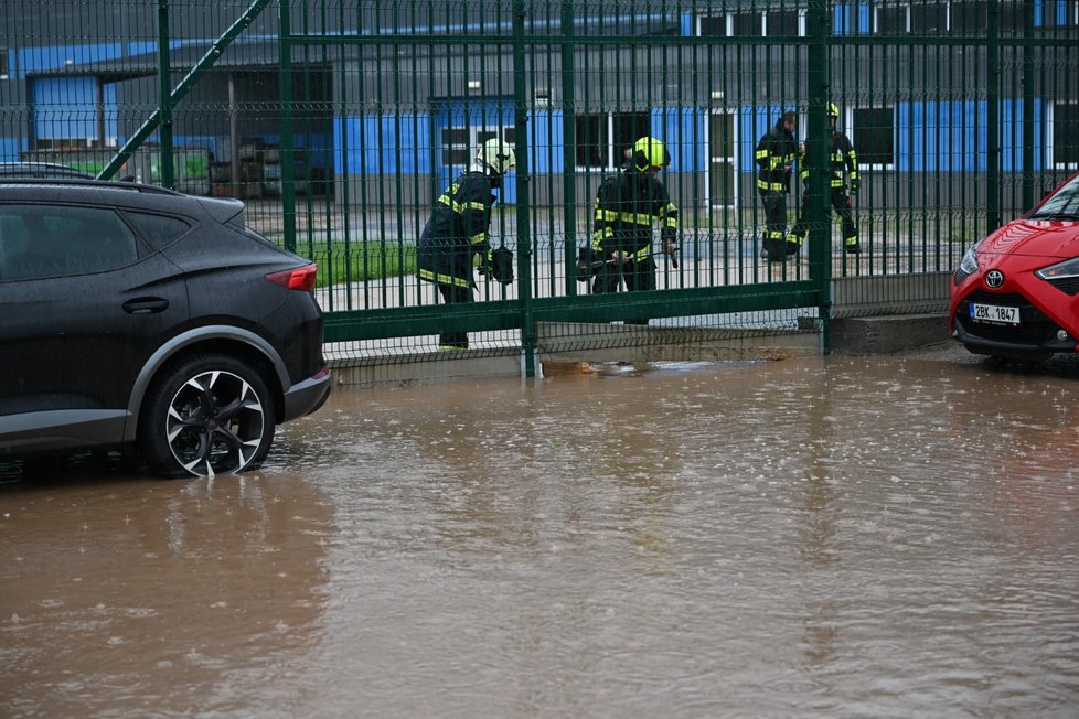Rozlitá voda u výrobní haly v Sudoměřicích, kde se hasiči snaží budovat provizorní hráze proti vodě vylité z Radějovky a Sudoměřického potoka.