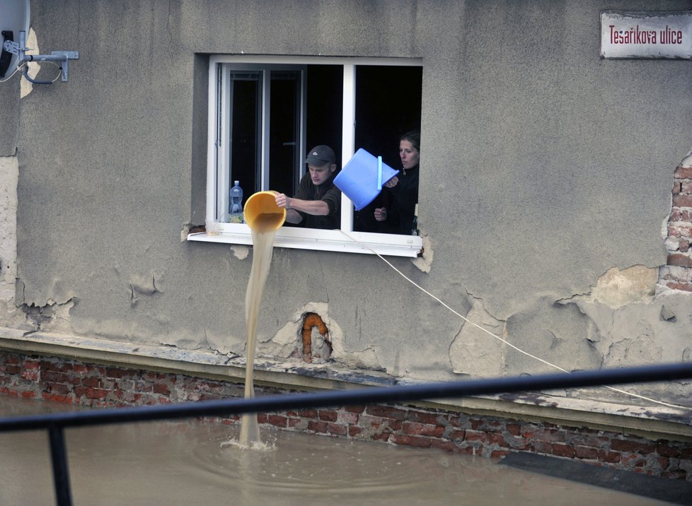 Lidé v Hranicích vylévají vodu ze zatopeného domu