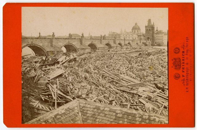 Dobová fotografie zachycuje naplaveniny, které v květnu 1872 přinesla velká voda do Prahy. Tříštily a těsnaly se zejména u mostů. Na fotografii je konkrétně Karlův most, který se naplaveným dřevem a nejrůznějším harampádím doslova ucpal.