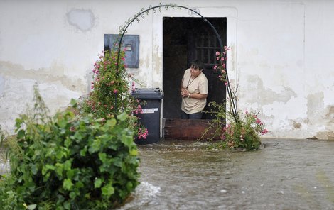 Žena v Dolní Řasnici na Liberecku vyhlíží ze zaplaveného domu