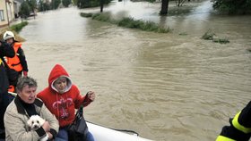 Dobrovolní hasiči a záchranáři evakuovali 18. května obyvatele ze zaplavených domů v Troubkách na Přerovsku. Na loďce jsou manželé Vlasta a Jiří Němčákovi, které povodeň postihla i před třinácti lety.