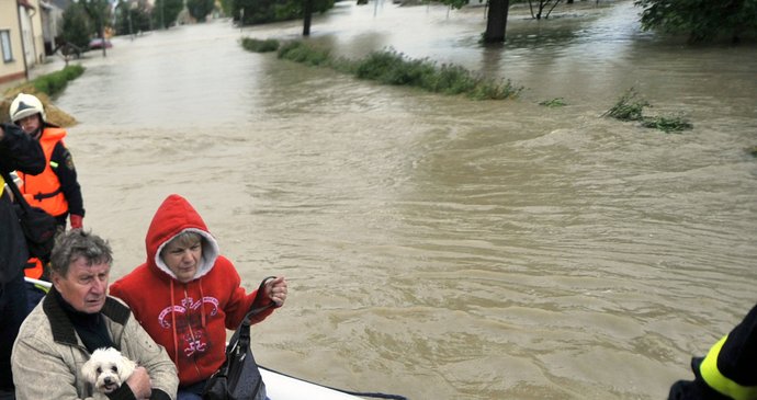 Dobrovolní hasiči a záchranáři evakuovali 18. května obyvatele ze zaplavených domů v Troubkách na Přerovsku. Na loďce jsou manželé Vlasta a Jiří Němčákovi, které povodeň postihla i před třinácti lety.