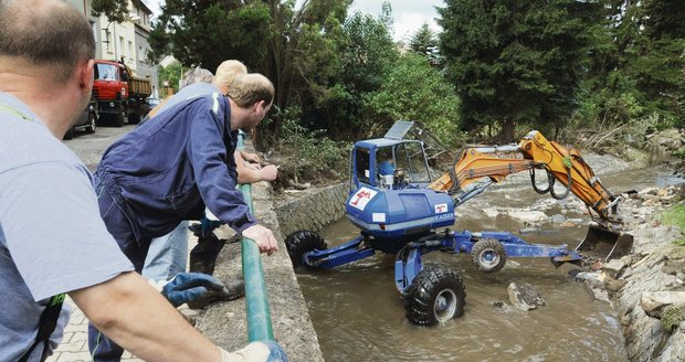 Bagr včera odklízel po sobotní povodni naplavené kamery z koryta říčky Bystrá v Benešově nad Ploučnicí