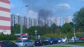 V Bohnicích vyhořel byt, začalo hořet v kuchyni. Hasiči hasili pouze vnitřkem domu, k místu požáru se nemohli dostat přes zaparkovaná osobní auta.