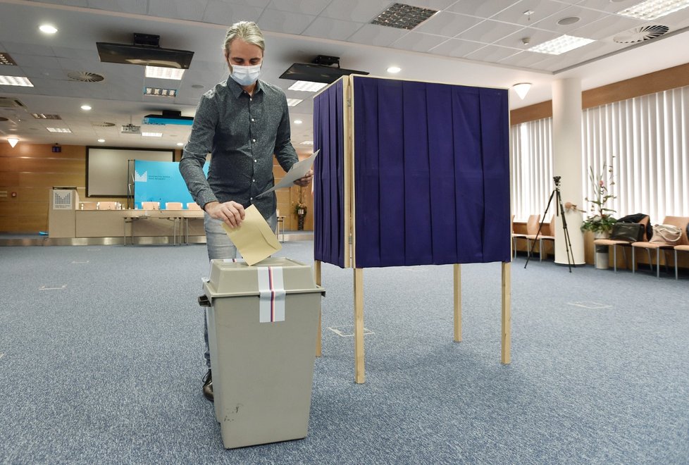 Členka simulované volební komise dezinfikuje psací potřeby v instruktážním spotu, který 4. září 2020 natočilo ministerstvo vnitra před říjnovými krajskými a senátními volbami.