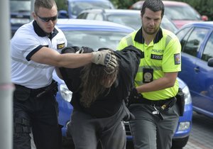 Policisté předvádějí pachatele na služebnu.