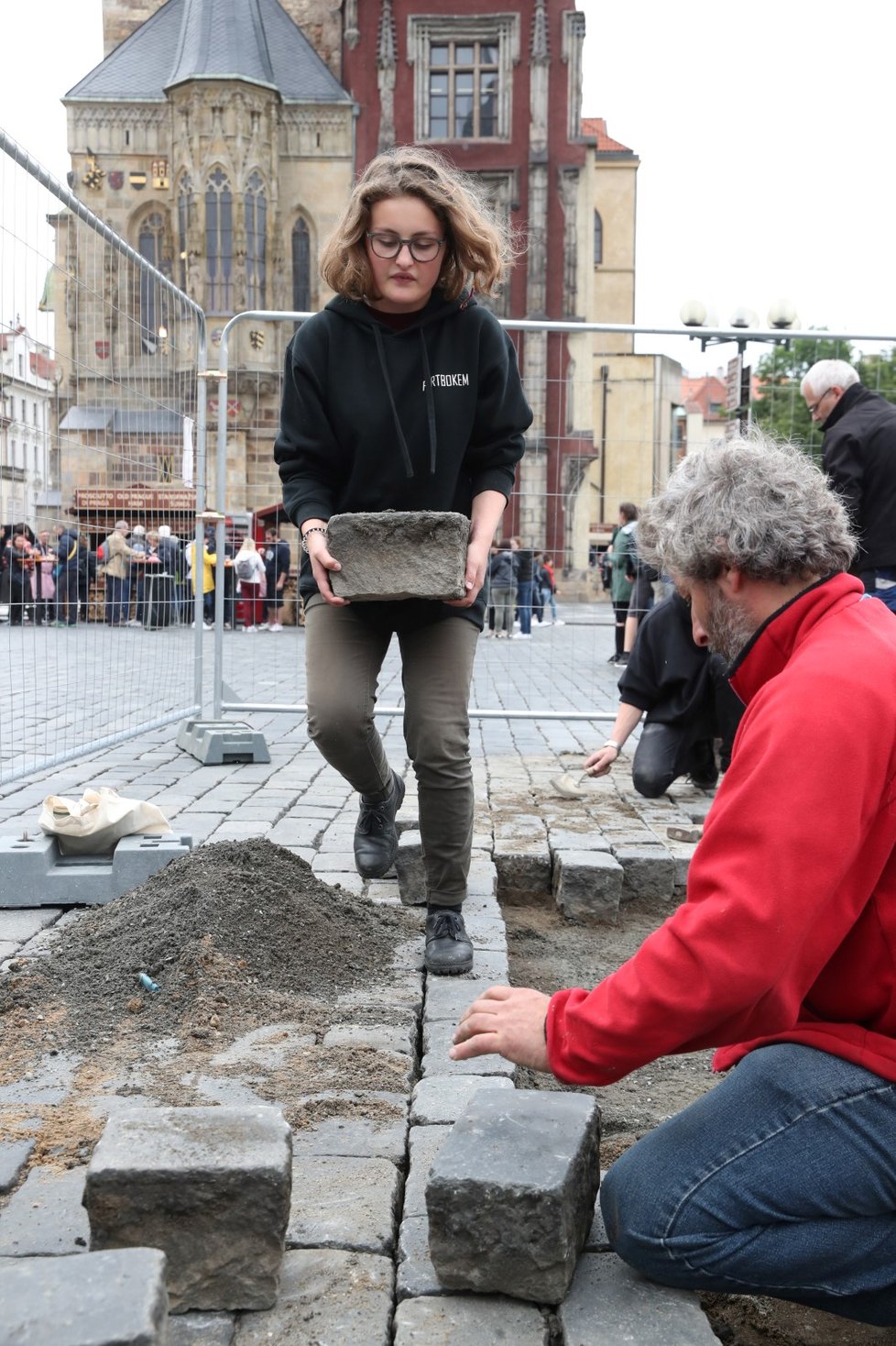 Sochař Váňa se spolupracovníky vrací kostky na Staroměstském náměstí zpátky.