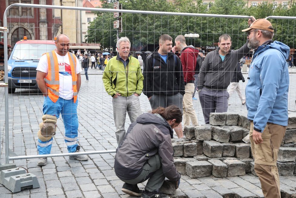 Sochař Váňa se spolupracovníky vrací kostky na Staroměstském náměstí zpátky.