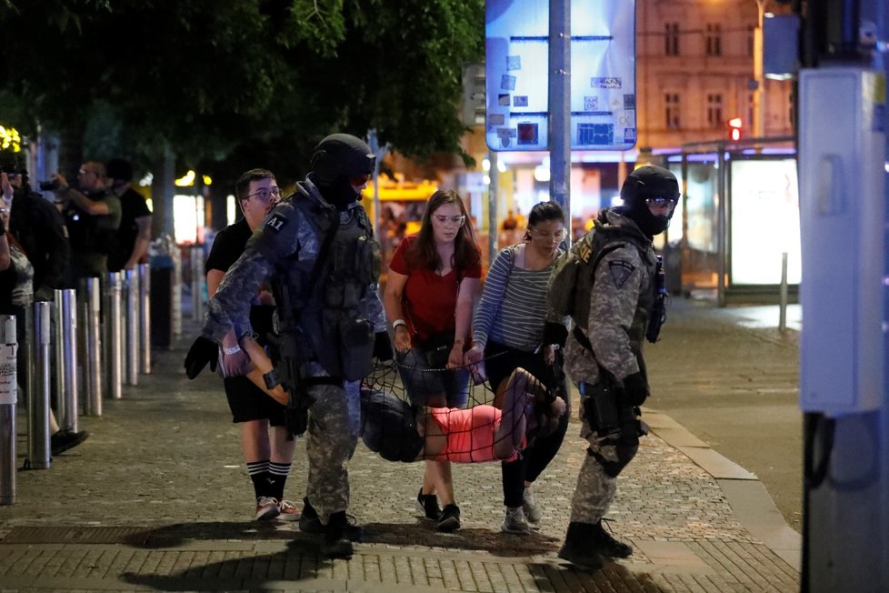 Figuranti pomáhají s vynášením zraněných.