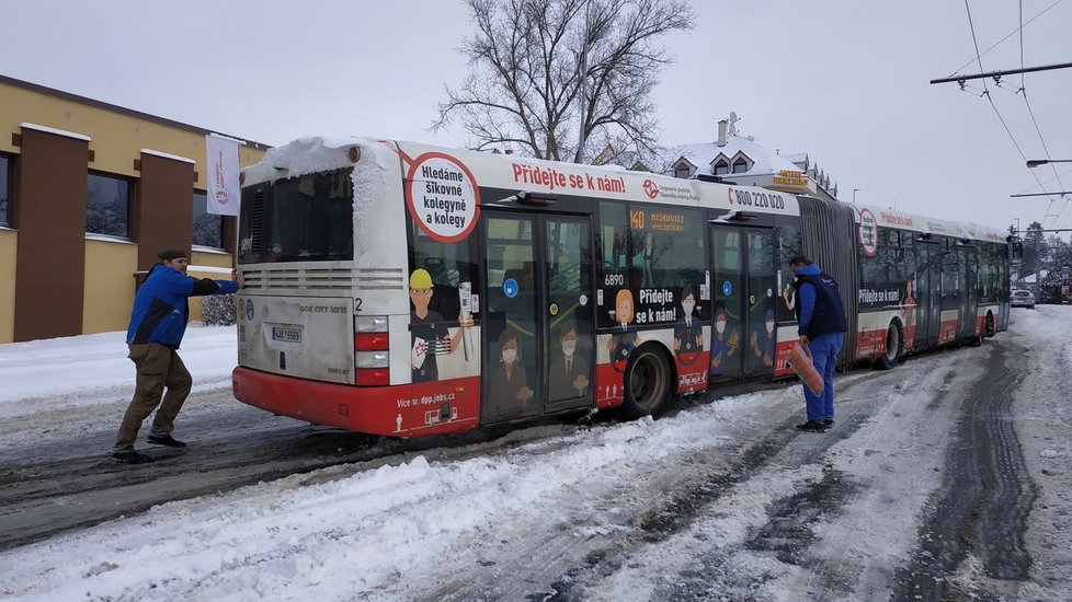 Kolemjdoucí pomohli vyprostit zapadený autobus v Prosecké ulici v Praze, 8. února 2021.