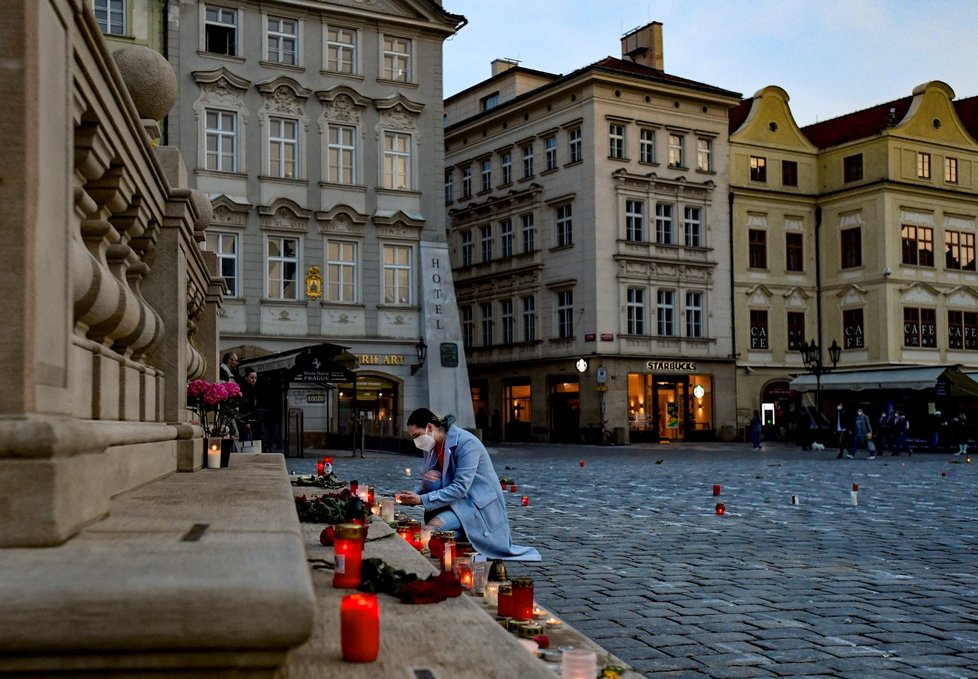 Lidé na Staroměstské náměstí přicházejí zapálit svíčky za zemřelé s covidem.