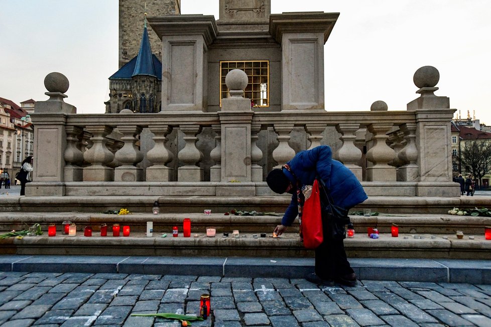 Lidé na Staroměstské náměstí přicházejí zapálit svíčky za zemřelé s covidem. (25. března 2021)