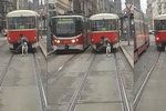 Muž na spřáhle tramvaje za sebou vláčí ještě psa na vodítku.