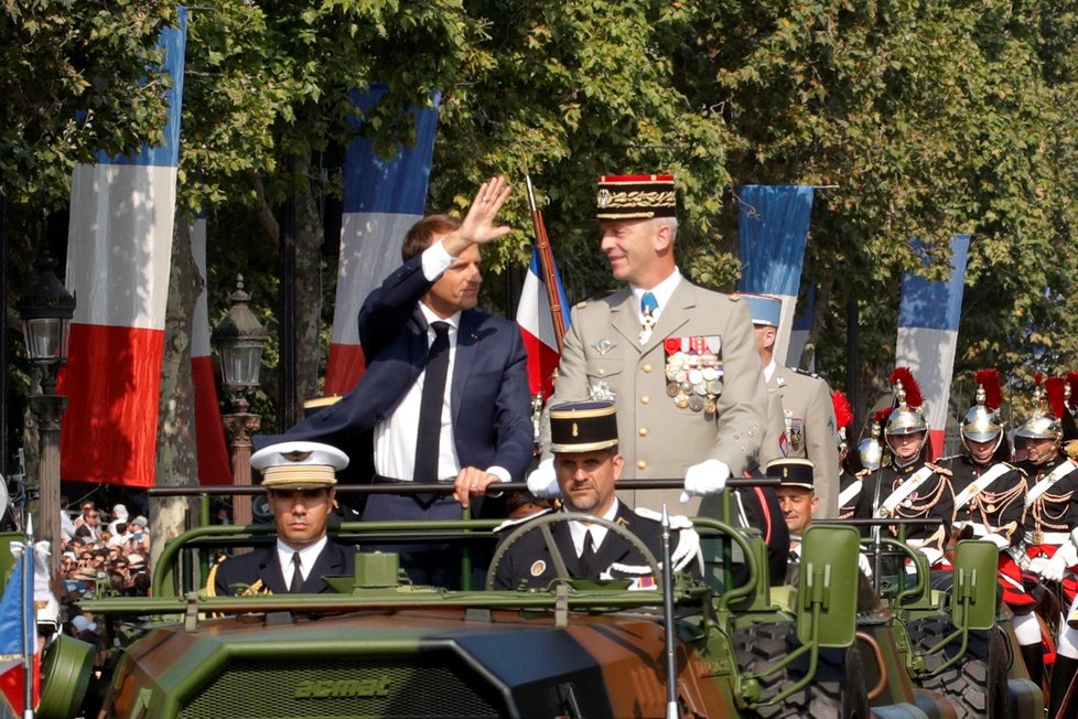 Prezident Emmanuel Macron mává divákům vojenské přehlídky u příležitosti oslav Dne Bastily.