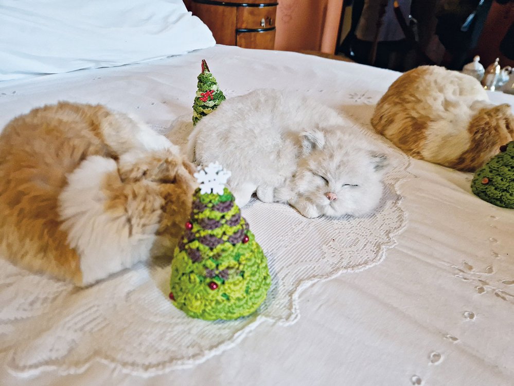 V zámecké ložnici hřejí postel autentické figurky spících koček s vánočními stromky