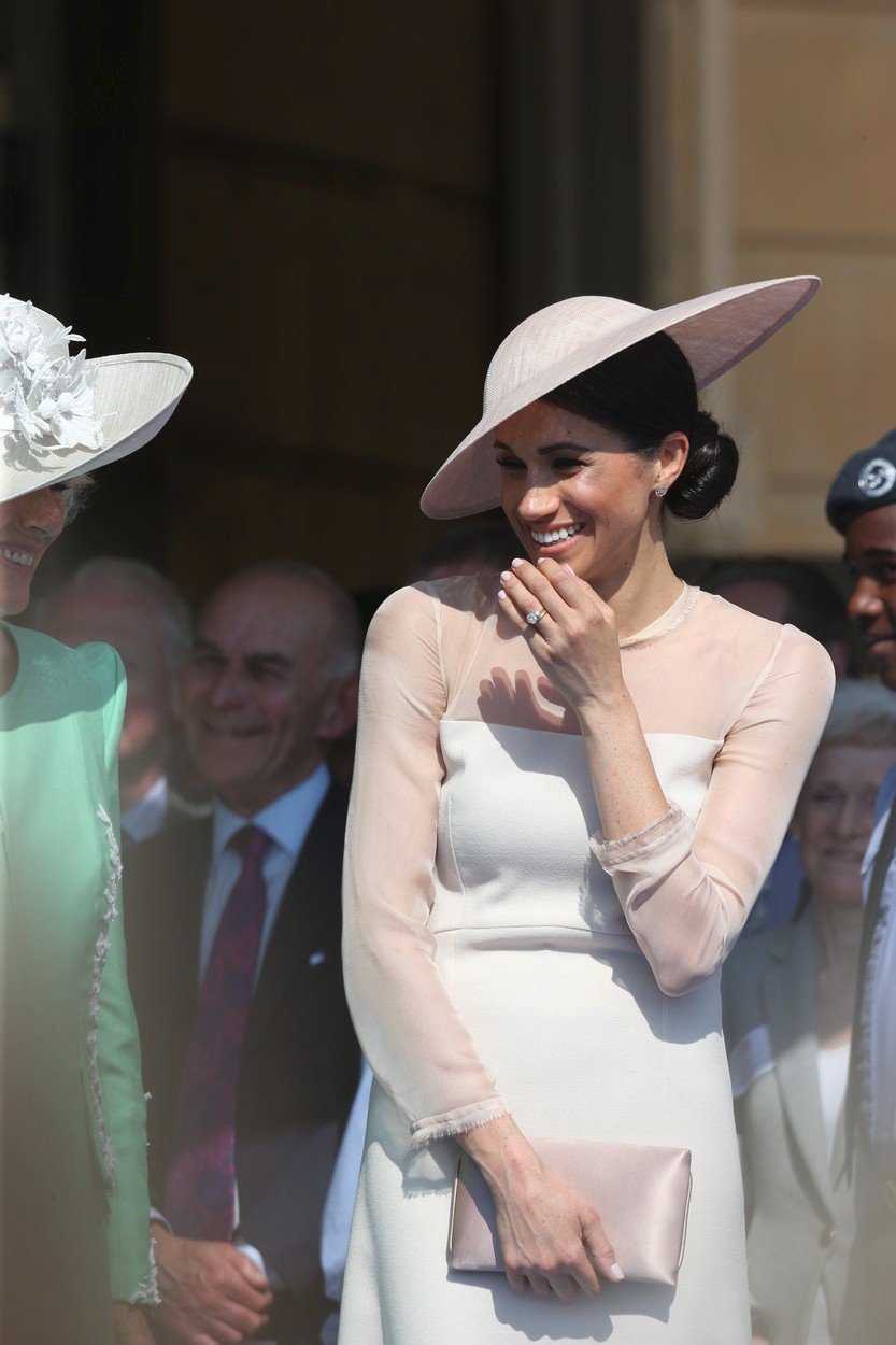 Vévodkyně ze Sussexu Meghan Markle drží psaníčko v oblasti bříška.