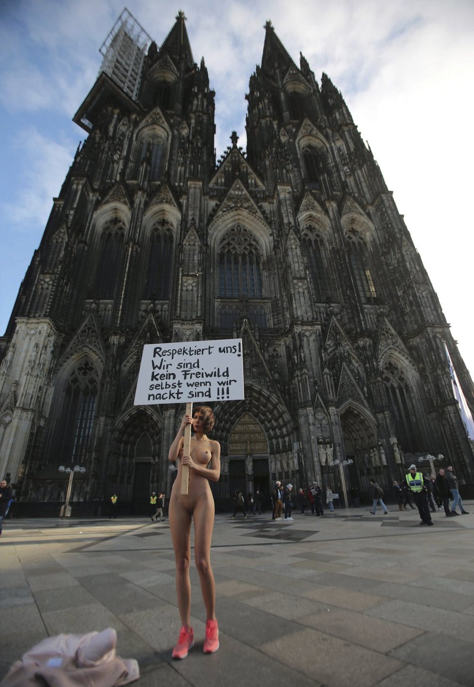 Švýcarská umělkyně Milo Moire s transparentem, se kterým nahá volala po respektu k ženám. Postavila se přitom v pátek před katedrálu v Kolíně nad Rýnem