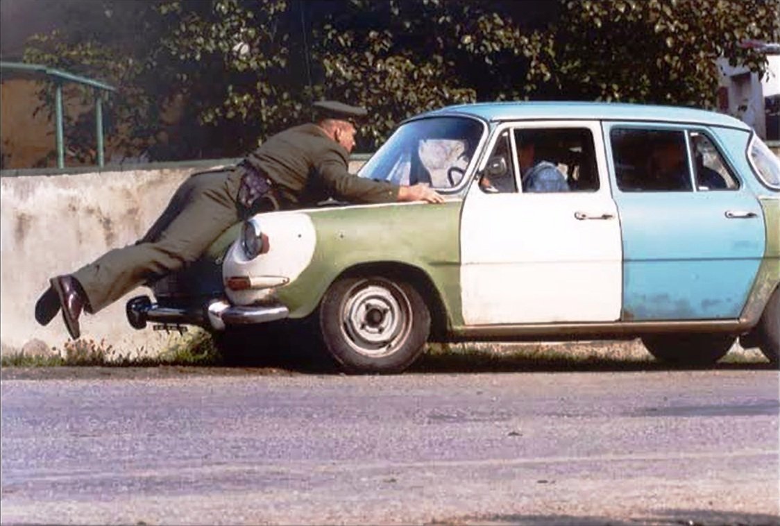 Václav Kopta jako policajt na kapotě škodovky. Srazil ho Liška.