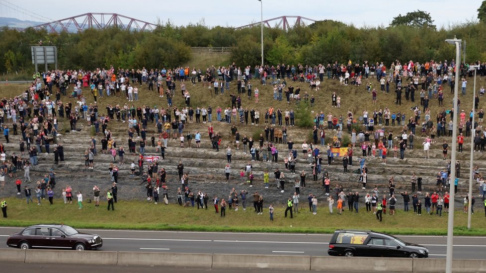 Lidé sledují pohřební vůz vezoucí rakev britské královny Alžběty na dálnici M90 za mostem Queensferry Crossing ve skotském Queensferry.