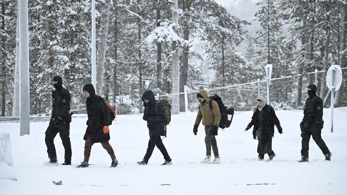 Finští pohraničníci eskortují migranty, kteří se objevili na severském hraničním přechodu Raja-Jooseppi