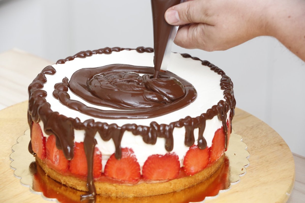 6. Po vychlazení nožem vykrojíme dort z formy a dozdobíme čokoládovou polevou. Hotový dort ozdobíme čerstvými jahodami.