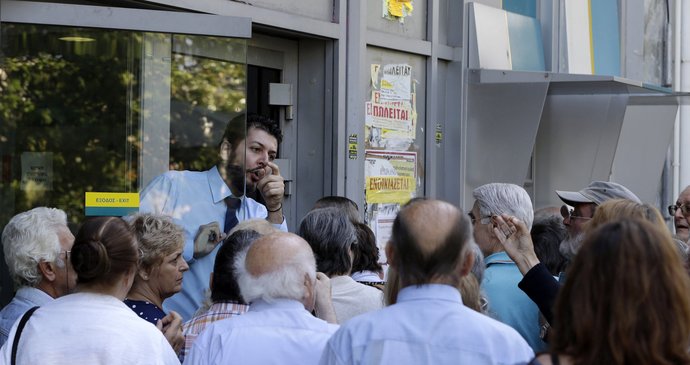 Zaměstnanec banky ukazuje seniorům, kde mají čekat