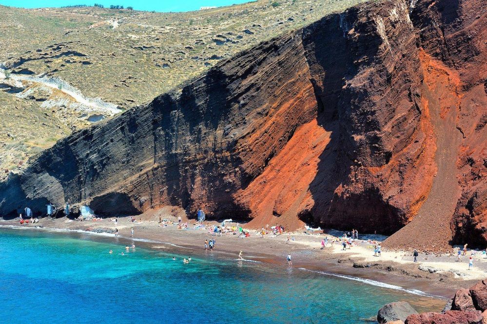 Díky barevnému vulkanickému písku, který je pokrývá, najdete atraktivních pláží na ostrově Santorini víc. Vedle těch černých je to i rudá, tedy slavná Red Beach, nad níž se tyčí červený skalní masiv a leží poblíž vesničky Akrotiri.