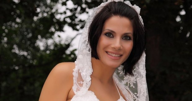 Eva Aichmajerová ve svatebních šatech vystavuje bříško a podvazek