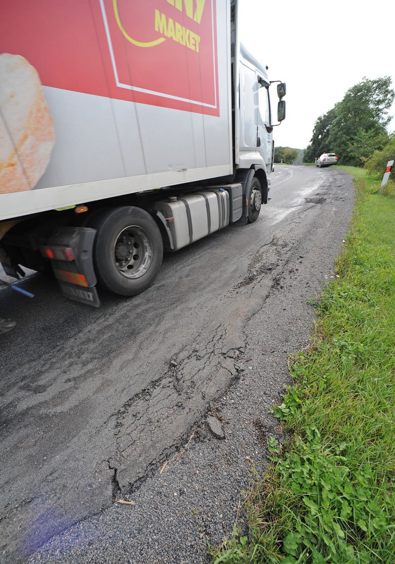 Koleje na silnici od těžké nákladní dopravy (v zatáčce je navíc zúžení) mají pořádnou hloubku.