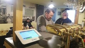 Jedna z pražských hospod v Holešovicích, kde se schází štamgasti. Majitel přesto, že jde o malý podnik, nezavřel, ale naopak se vybavil více roličkami papíru na účtenky.