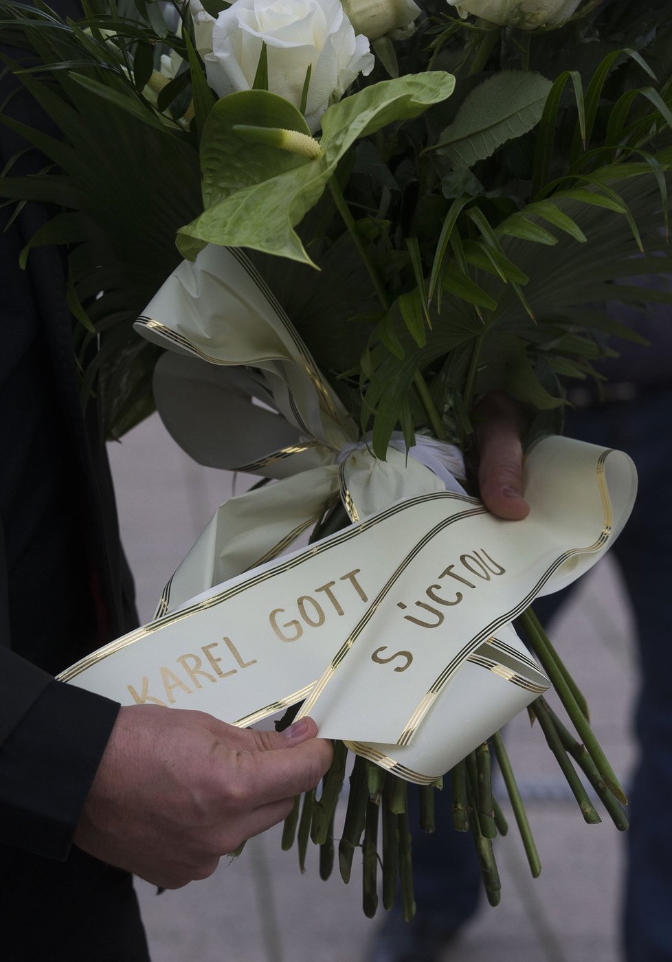Bodyguard nese smuteční kytici se vzkazem od Karla Gotta.