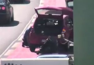 Strážníci mění prasklou pneumatiku u auta, za jehož volantem zkolaboval řidič.