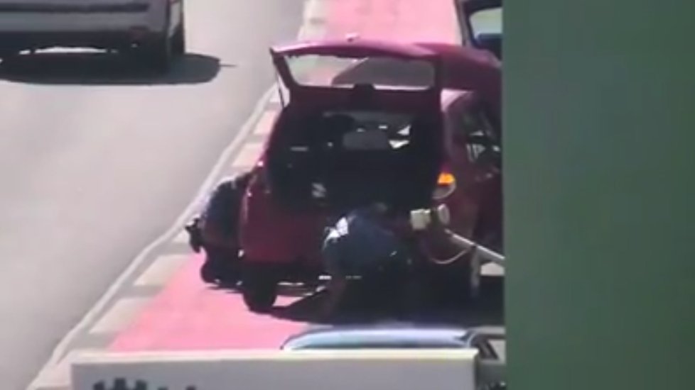 Strážníci mění prasklou pneumatiku u auta, za jehož volantem zkolaboval řidič.