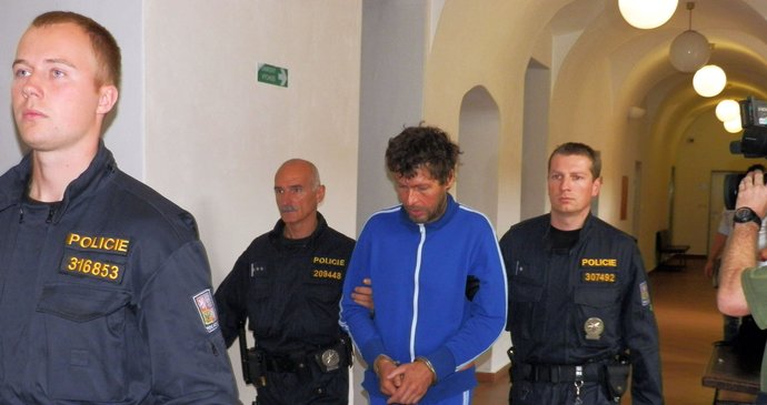 Robert Leicht v modré kombinéze v doprovosu policistů u soudu v Hradci Králové