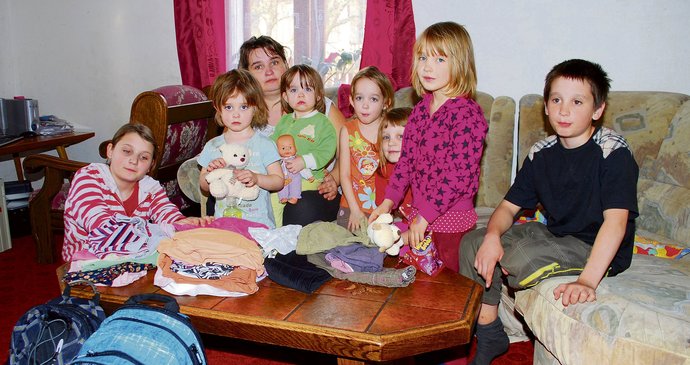 Zdeňka Peterová (39) se svými dětmi nad věcmi, které rodina dostala od čtenářů Blesku. Zleva Iveta (12), Radka (4), Klára (1), Lucka (5), Bára (7), Šárka (6) a Marek (11). Na snímku chybějí dvě nejstarší dcery Karolína (15) a Pavlína (17), které při návštěvě fotografů nebyly zrovna doma.