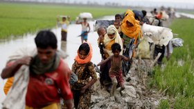 Rohingyjští uprchlíci prchají ze země a brodí se bahnem.