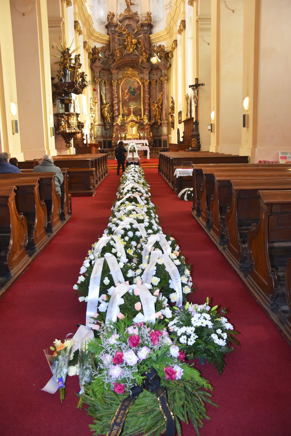 Při pohřbu zastřelené ženy (†37) byl plný kostel smutečních věnců a květin.