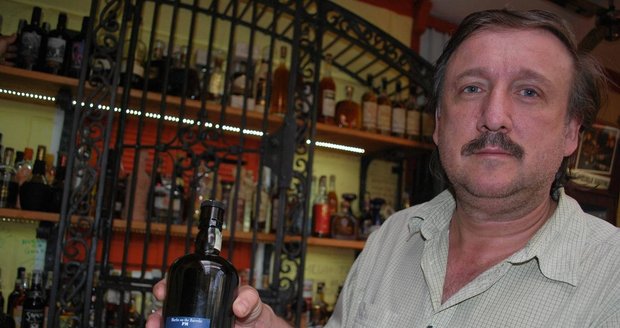 Radek Novotný ukazuje rum z malého lihovaru v Havaně, který se tam balí exkluzivně pro brněnskou stejnojmennou restauraci. Za ním je za kovanou mříží rumotéka s 364 druhy rumu!