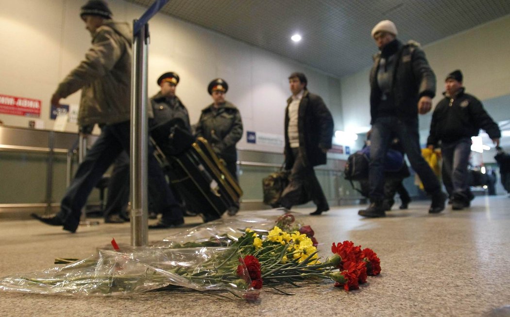 V letištní hale lidé pokládají květiny