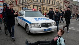 Jeden z příznivců opozice blokuje policejní auto během protiputinovské demonstrace v Petrohradě (5.5.2018)