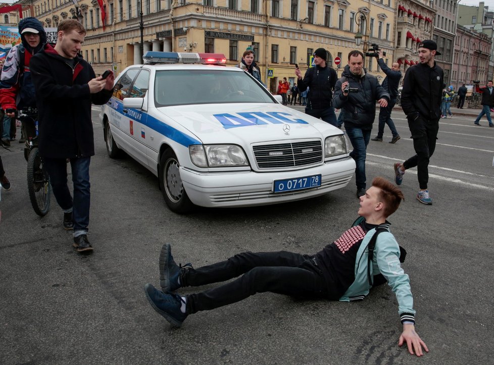Jeden z příznivců opozice blokuje policejní auto během protiputinovské demonstrace v Petrohradě (5. 5. 2018)