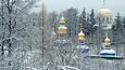 Pohled na Pskovsko-pečerský klášter z klášterní zahrady na Svatém kopci. Modré kupole se zlatými hvězdami jeskynního kostela Zesnutí přesvaté Bohorodice mají v tradicích ukrajinského baroka připomínat Kyjevsko-pečerskou lávru, nejstarší a nejznámější pravoslavný klášter Kyjevské Rusi, odkud na severozápadní okraj Ruska přišli první mniši. V pozadí se tyčí zlaté kupole katedrály archanděla Michaela.