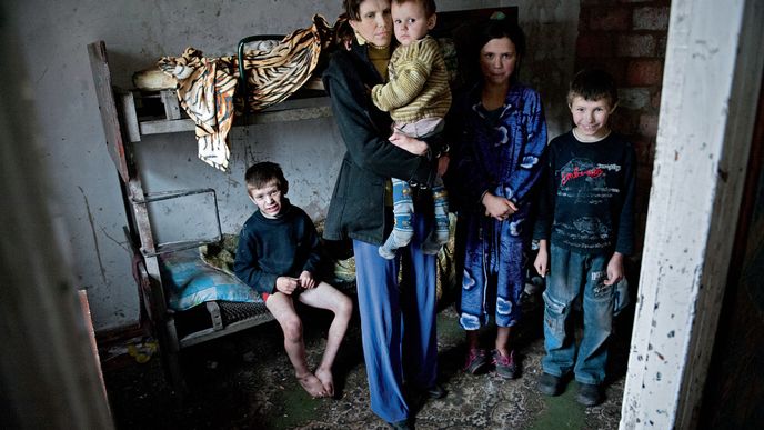 Pětatřicetiletá  Oxana vychovává své děti sama. V náručí drží nejmladšího  Žeňu (2.5). Vedle stojí dcera Vika (12) a synové Saša (10) a vlevo Sergej (6). Jejich dům se nachází vedle ostřelovaného města Popasné na území kontrolovaném ukrajinskou armádou, správní středisko je však na území ovládaném separatisty, a tak rodina nedostává už od léta ani kopejku přídavků na děti ani mateřské. Oxaně se v listopadu podařilo získat práci v  umývárnách místního dolu, za práci bere  měsíční mzdu 1200 hřiven (1400 Kč), což bude jediný zdroj peněz pro celou domácnost.