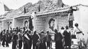 Tibetští venkované v září 1959 v městečku Čhušul nedaleko Lhasy sledují  umělce, jak malují Mao Ce-tungovy portréty a propagandistické texty 