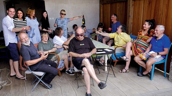 U Trojanů na náměstí. Slavonice, malebné městečko na hranicích s Rakouskem, se počtvrté na pět dní proměnilo v centrum filmového a hudebního festivalu. Letos tu například proběhla světová premiéra filmu Jana Svěráka Po strništi bos. Myšlenka na Slavonice Fest vznikala v místní hospodě Besídka, důvod byl jasný: spousta Sklepáků a jejich přátel si právě tam a v okolních obcích pořídila chalupy, v případě několika z nich, jako je rodina Trojanových, dokonce měšťanský dům na náměstí. Právě u nich festival od roku 2014 „pečou“. Na momentce u Trojanových doma poznáte spoustu známých tváří: Filmový producent Ondřej (sedící vpředu) a Bára Trojanová (stojící s lahví šumivého nápoje), její tatínek, chirurg Pavel Pafko (sedící vpravo), vedle něj Lucie a Jaroslav Rónovi, Ivan Trojan s manželkou Klárou, vlevo vedle Lukáše Pavláska pak sedí slavonické duše Martin Ceplecha a Jan Boháč, nad nimi herec Václav Jiráček s přítelkyní.