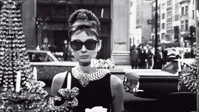 Audrey Hepburnová ve filmové adaptaci novely Trumana Capoteho Snídaně u Tiffanyho z roku 1961 stojí před výlohou slavného zlatnictví Tiffany 