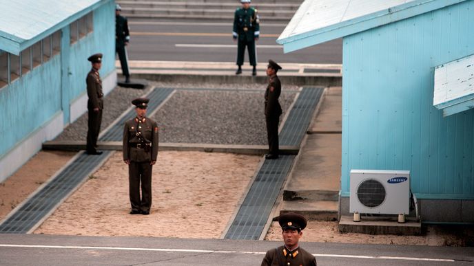 POHLED ZE SEVERNÍ KOREJE V popředí jsou čtyři severokorejští vojáci, za nimiž probíhá demarkační linie, která rozděluje obě znepřátelené země. Je to jediné místo na Korejském poloostrově, kde vojenské síly obou zemí stojí tváří v tvář.