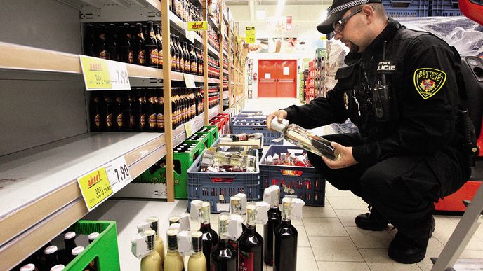 Strážník městské policie kontroluje okolkovanou láhev s alkoholem