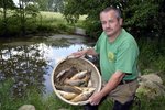 Karel Bobál smutně loví mrtvé ryby, které plavou po hladině rybníka