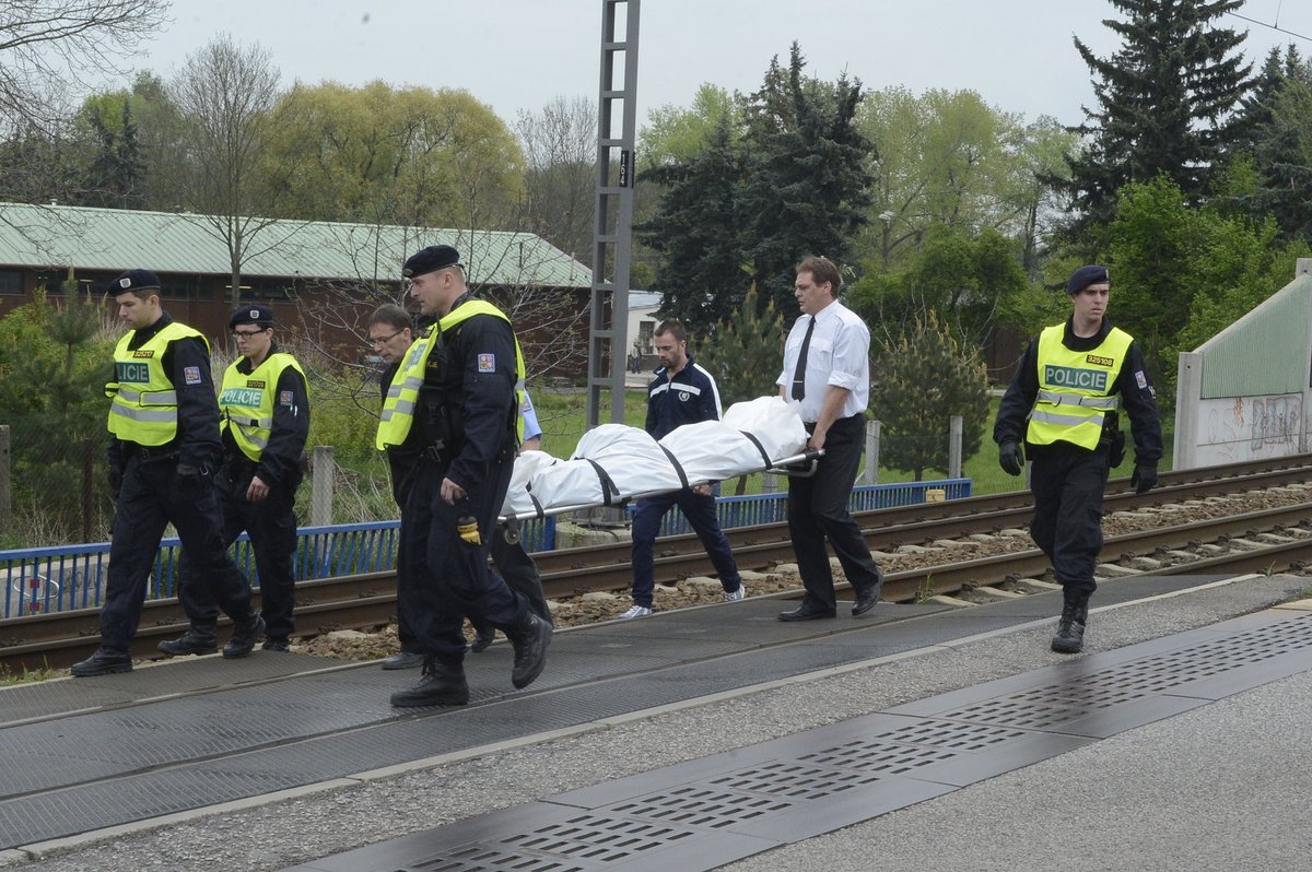 Zřízenci odnášejí za asistence policie ostatky Bartošové z kolejí, kde vyhasl její život.